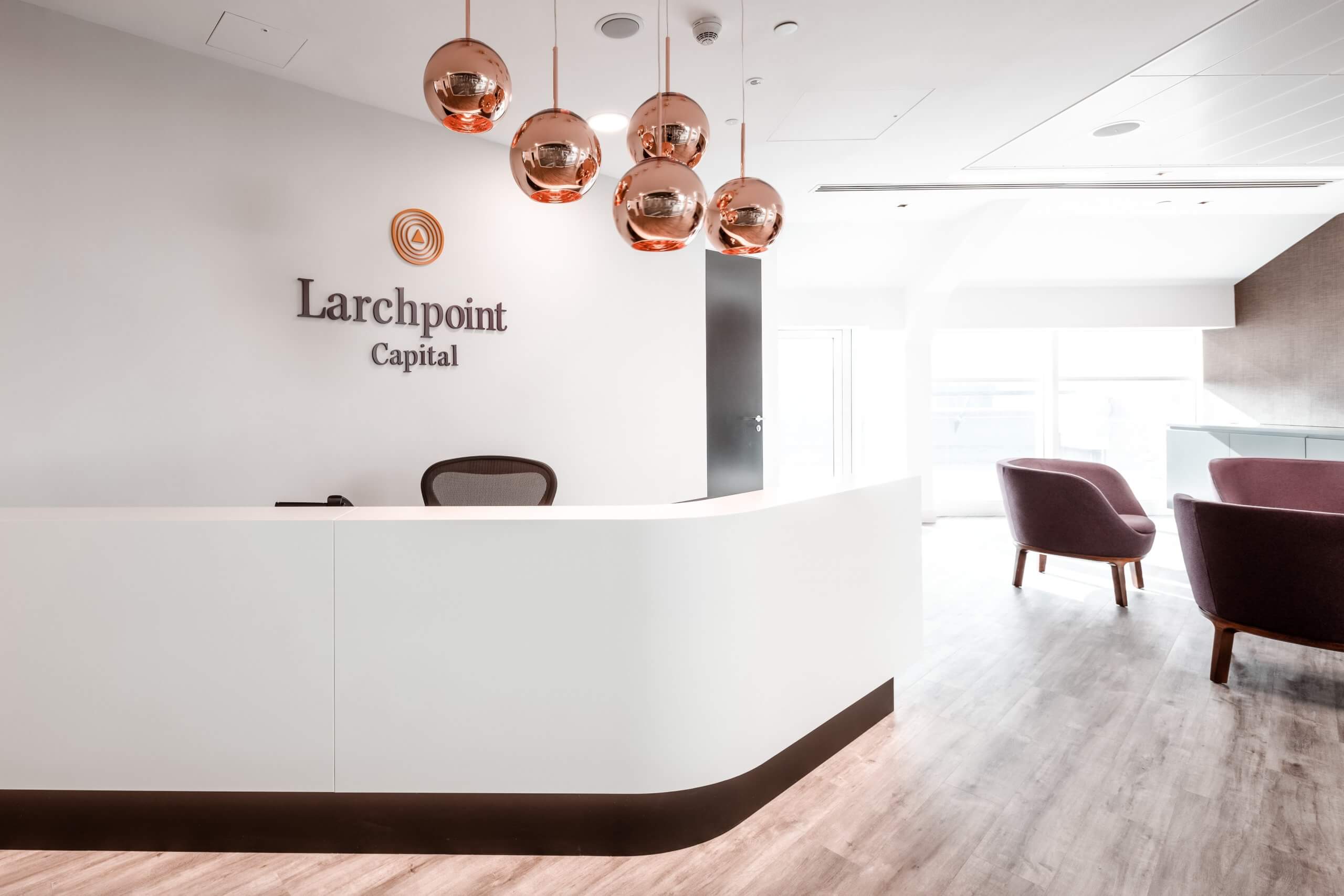 Larchpoint Capital Logo with copper light fixtures above a reception desk.